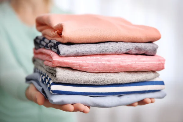 Mulher segurando roupas dobradas nas mãos, close-up — Fotografia de Stock