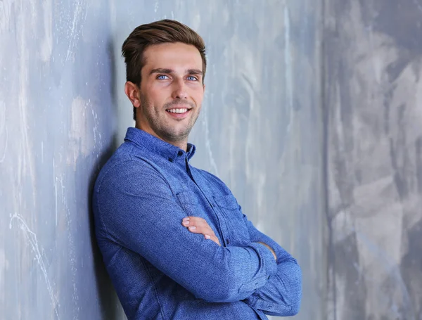 Молодий щасливий бізнесмен на сірому фоні стіни — стокове фото