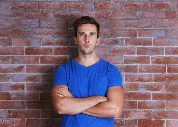 Joven hombre guapo sobre fondo de pared de ladrillo —  Fotos de Stock