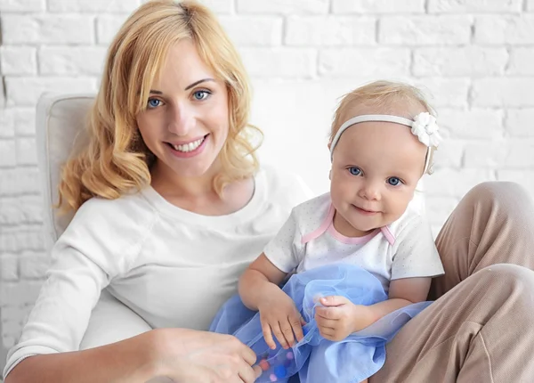 Mutter mit Tochter sitzt im Sessel auf weißem Backstein-Hintergrund — Stockfoto