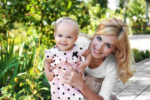 Happy mother with daughter resting in park on sunny day — Stock Photo, Image