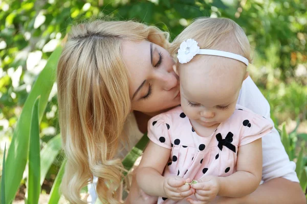 Happy mother with daughter resting in park on sunny day — Stock Photo, Image