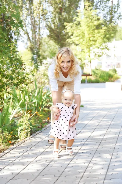 Lycklig mamma med dotter vilar i parken på solig dag — Stockfoto