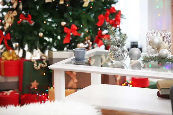 Чашки и стеклянные вазы с рождественским декором на белом столе в гостиной оформлены на Рождество — стоковое фото
