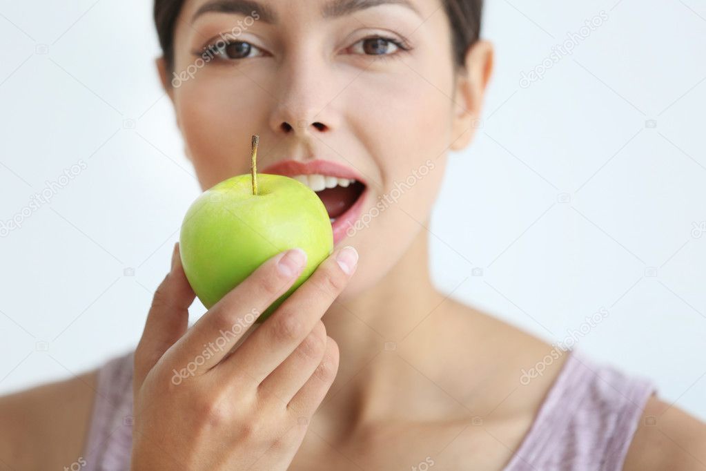 Young woman eating green apple, close up