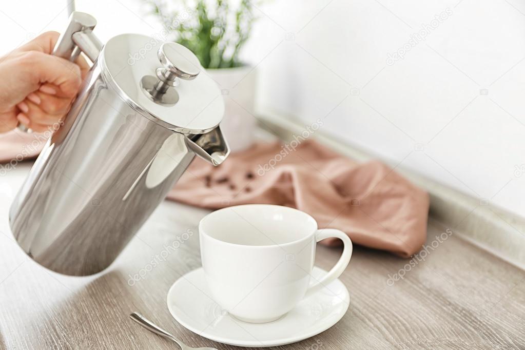 Fresh coffee pouring from pot into cup