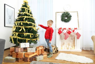 Evdeki Noel ağacını süsleyen sevimli küçük çocuk.