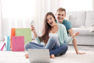 Kredi kartı ve katta oturan ve alışveriş yapma laptop ile mutlu çift