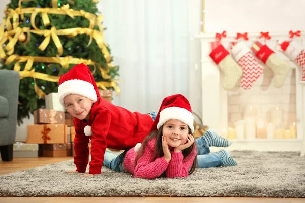 Lindos niños pequeños en sombreros de Santa en casa —  Fotos de Stock