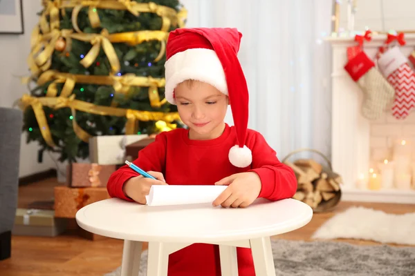 Carino piccolo ragazzo scrittura lettera a Babbo Natale a tavola — Foto Stock