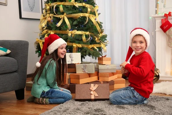 Χαριτωμένα παιδάκια στα καπέλα Santa με Χριστουγεννιάτικο δώρο στο σπίτι — Φωτογραφία Αρχείου