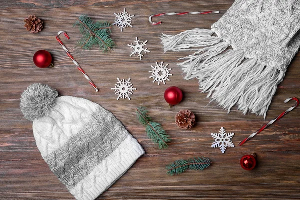 Knitted cap, scarf and Christmas decor on wooden background — Stock fotografie