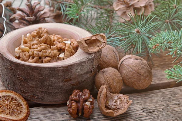 Composition of bowl with walnuts and natural decor on wooden background, close up view — Stockfoto