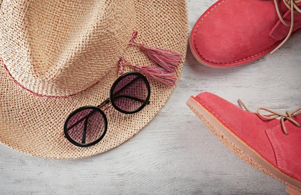 Червоне взуття, солом'яний капелюх на дерев'яному тлі. Концепція продажу — стокове фото
