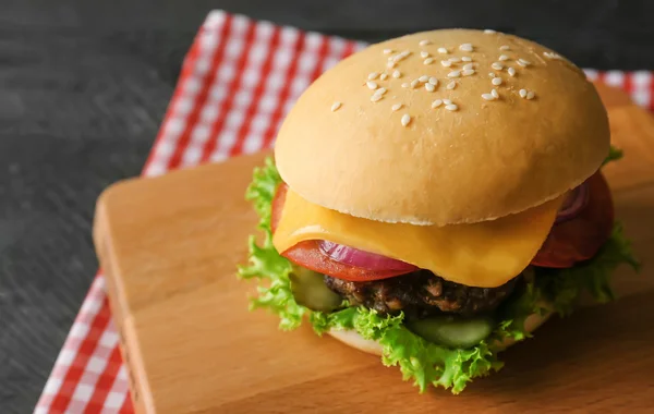 Sabrosa hamburguesa sobre tabla de madera —  Fotos de Stock