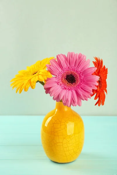 Vaso giallo con bouquet di bellissimi fiori di gerbera su sfondo chiaro — Foto Stock