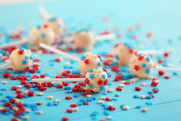 Delicious lollipops and scattered sprinkles on blue wooden background — Stock Photo, Image