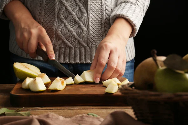 Woman slicing pear on wooden board — Stock Photo, Image