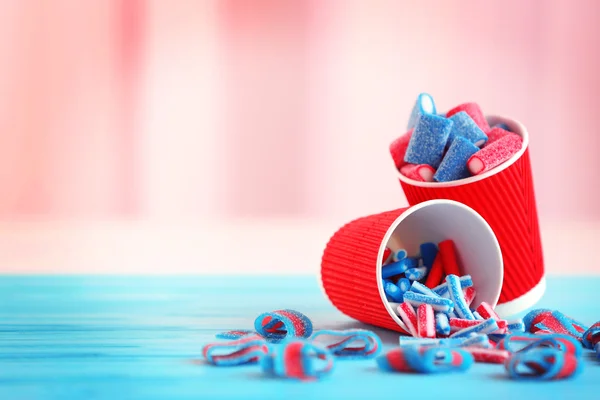 Смачні цукерки в паперовій чашці на синьому дерев'яному столі — стокове фото