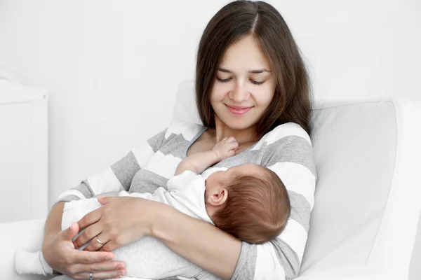 Portrait of pretty young woman holding sleeping baby at home — Stock Photo, Image