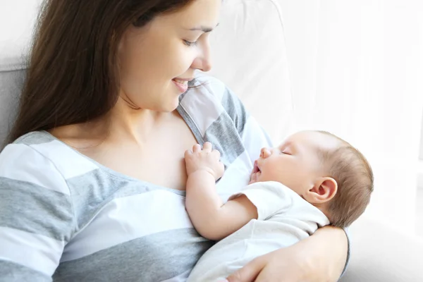 Potret wanita muda cantik menggendong bayi tidur di latar belakang cahaya — Stok Foto