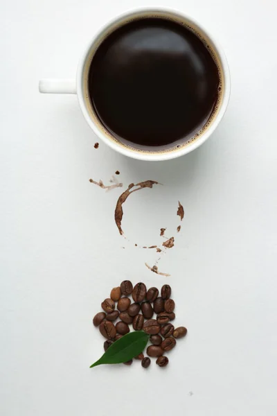 Taza de café con granos, hoja verde y mancha sobre fondo blanco, primer plano — Foto de Stock