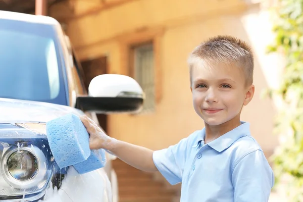 Kleine jongen wassen auto met spons op straat — Stockfoto