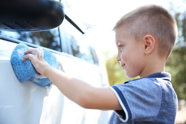 Kleine jongen wassen auto met spons op straat — Stockfoto