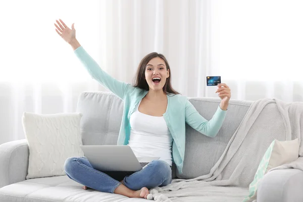 Young woman sitting on sofa and making online shopping — Stock Photo, Image