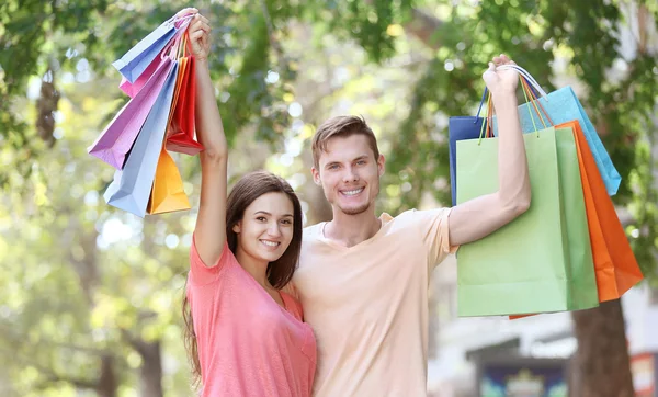 Lyckliga par med färgglada shoppingkassar i park — Stockfoto