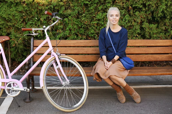 Hezká mladá cyklista sedí na lavičce v parku — Stock fotografie