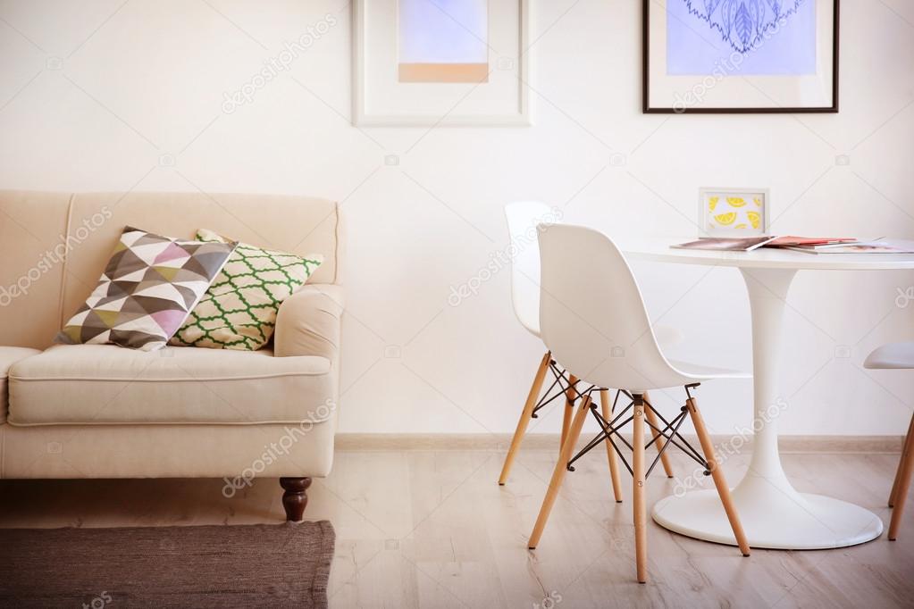 Beautiful modern interior with sofa, white table and chairs