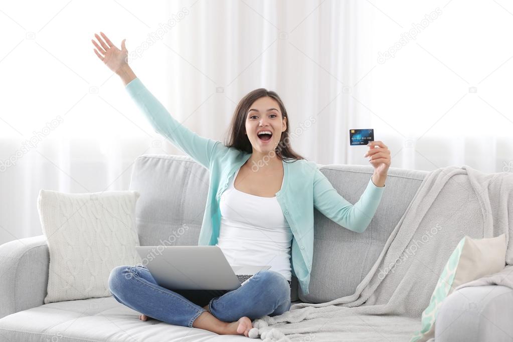 Young woman sitting on sofa and making online shopping