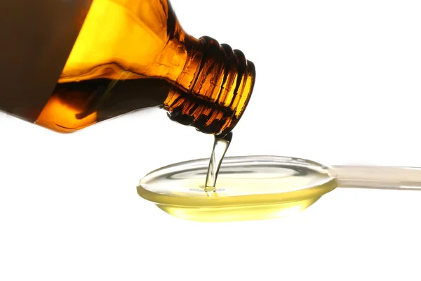 Despejo de óleo de peixe de garrafa em colher, isolado sobre branco — Fotografia de Stock