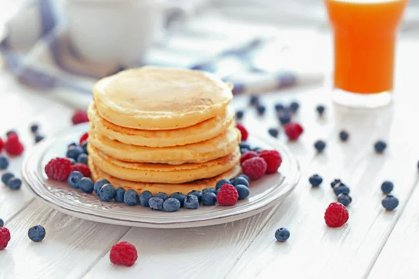 Plate with tasty pancakes and berries on wooden table — Stock Photo, Image