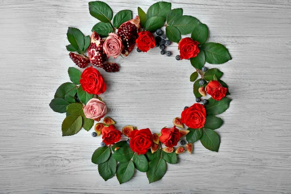 Složení růže, fíky, borůvky a granátová jablka kousky na dřevěné pozadí — Stock fotografie