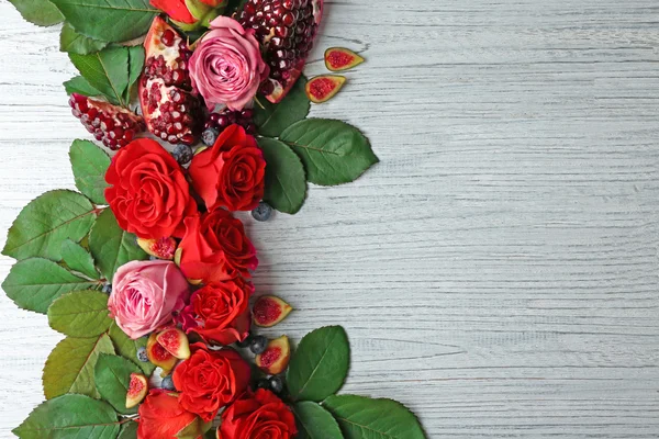 Složení růže, fíky, borůvky a granátová jablka kousky na dřevěné pozadí — Stock fotografie