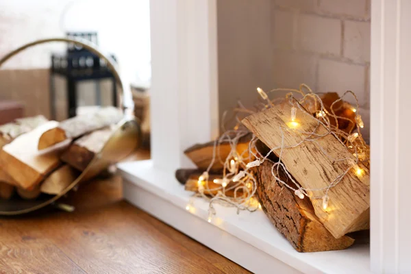 Tronchi e luci nel caminetto decorativo di Natale, primo piano — Foto Stock
