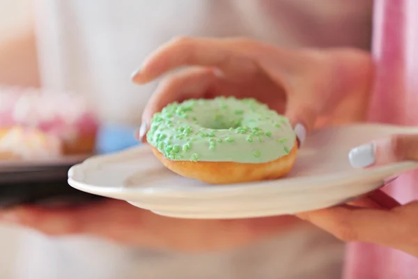 접시에서 맛 있는 도넛을 복용 하는 여성 손 가까이 보기 — 스톡 사진