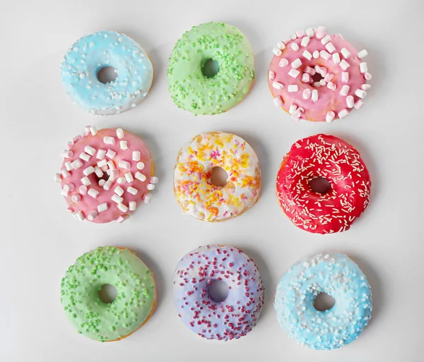 Deliciosas rosquillas con coloridos espolvoreos sobre fondo claro — Foto de Stock