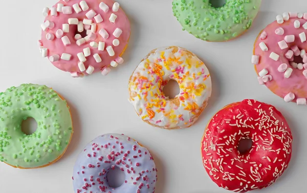 Donuts savoureux avec des aspersions colorées sur fond clair — Photo