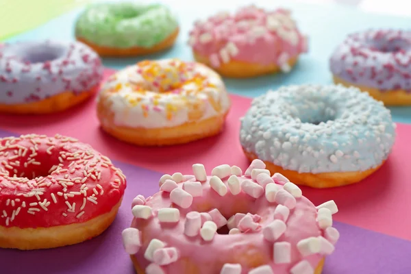 Donuts saborosos com polvilhas sobre fundo colorido — Fotografia de Stock