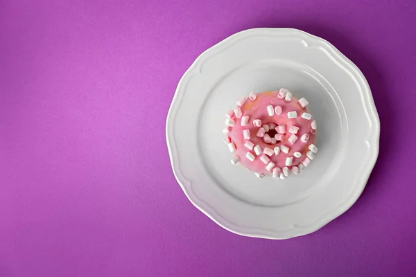 Тарелка с вкусным пончиком на цветном фоне — стоковое фото