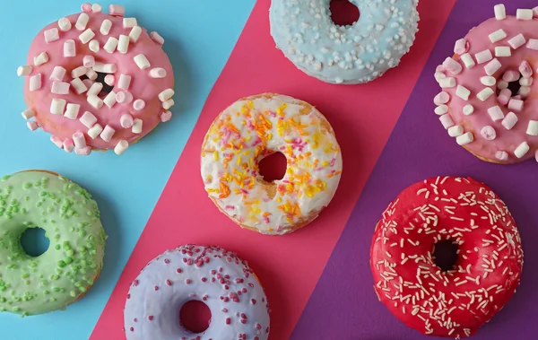 Deliciosas rosquillas con salpicaduras sobre fondo colorido — Foto de Stock