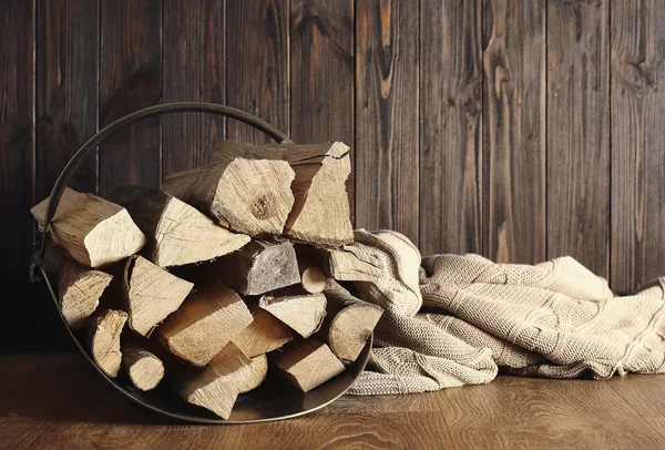 Cesta com lenha sobre fundo de madeira — Fotografia de Stock