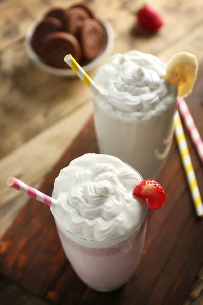 Muz ve çilek üzerinde ahşap masa portre ile lezzetli milkshakes — Stok fotoğraf