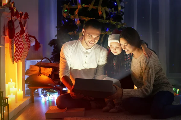 Family opening presents near fireplace decorated for Christmas