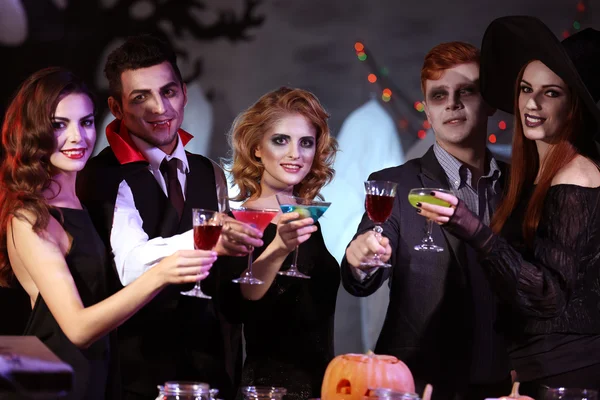 Young people in costumes drinking cocktails at Halloween party — ストック写真