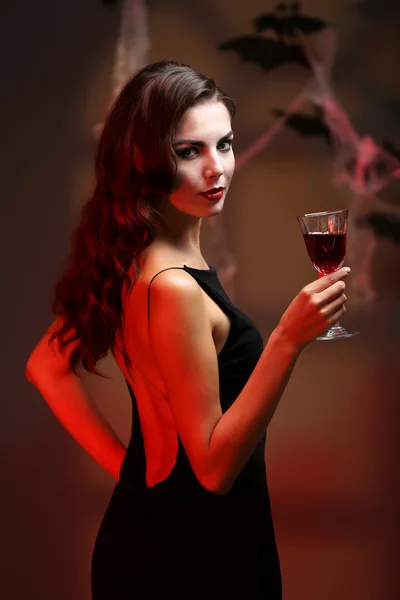 Young woman dressed as vampire for Halloween party, on dark background — Stock Photo, Image