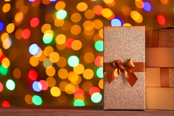 Caixas com presentes de Natal na superfície de madeira contra luzes desfocadas — Fotografia de Stock